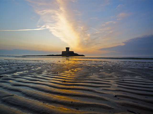 Rocco Tower at sunset is in the middle of St Ouen's Bay