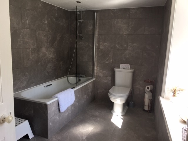 House bathroom with shower over bath, basin and WC.