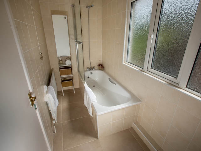 Bathroom with bath with shower over bath and separate basin