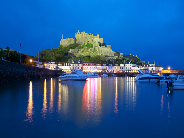 Mont Orgueil Castle at night, with restaurants and pubs nearby on Gorey Pier