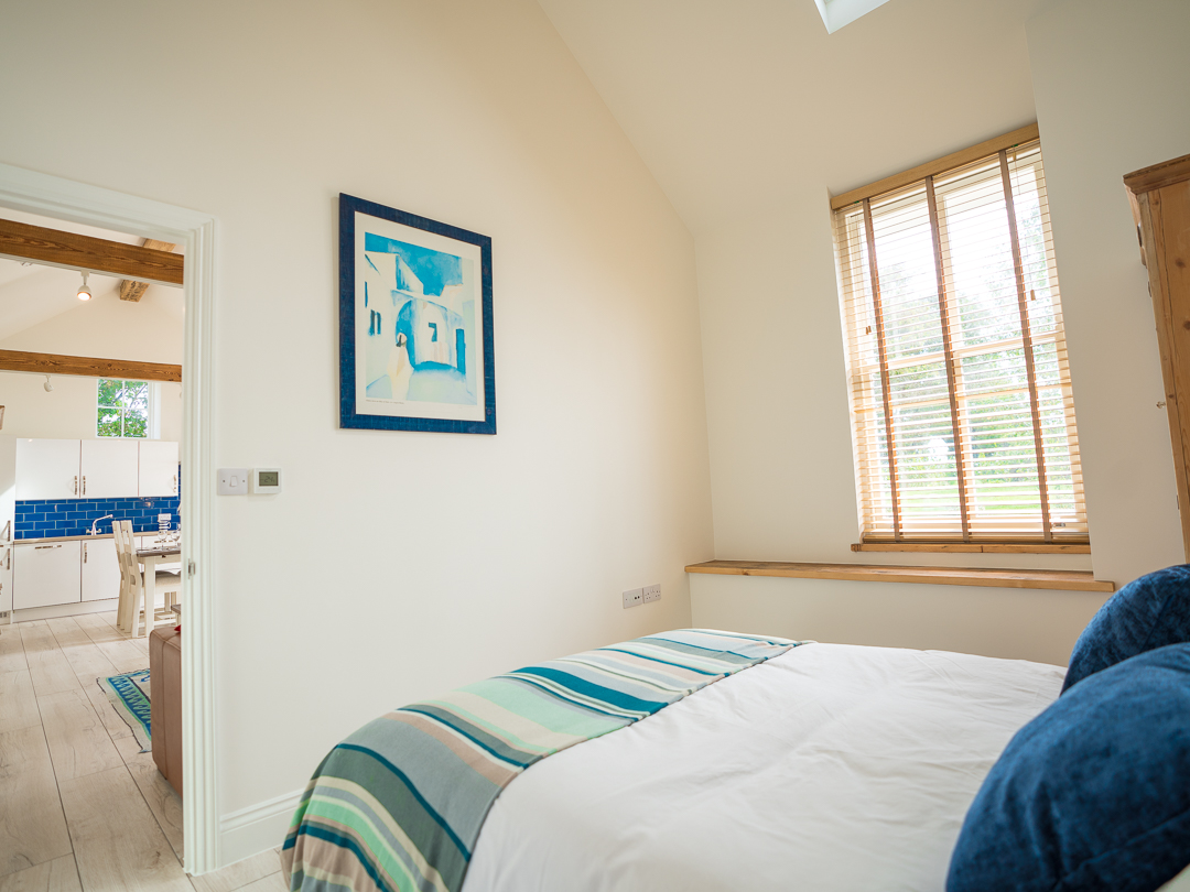 Master bedroom with view into open plan lounge, kitchen and diner