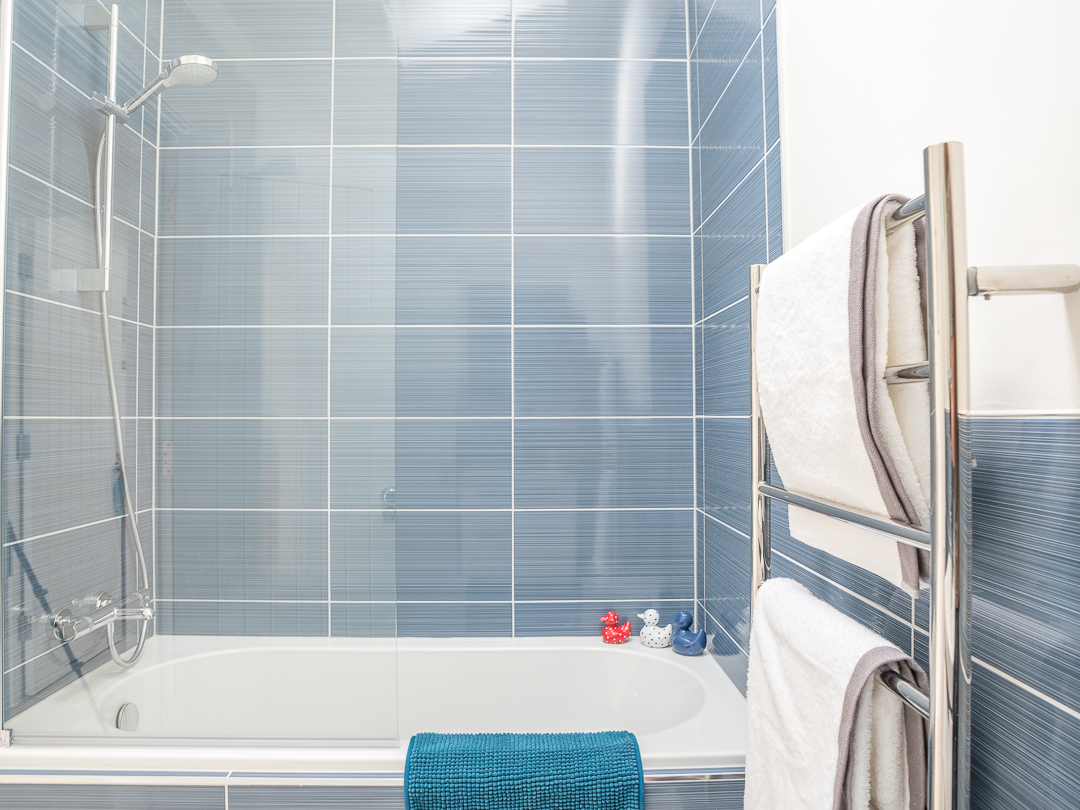 Bathroom with shower over small bath, basin and toilet