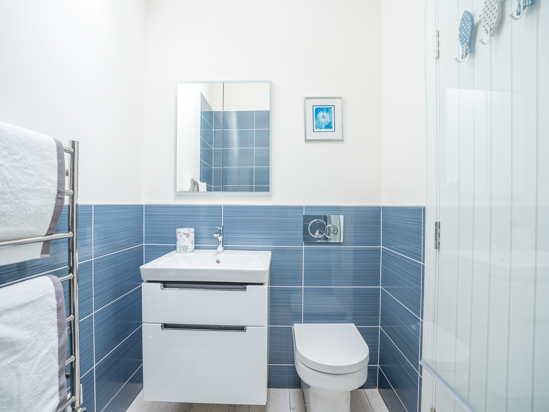 Bathroom with shower over small bath, basin and toilet