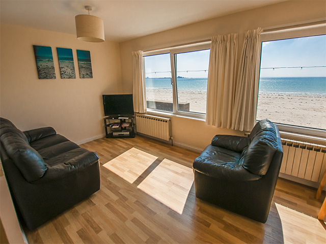 Lounge area of open plan living room overlooking the beach of St Aubin